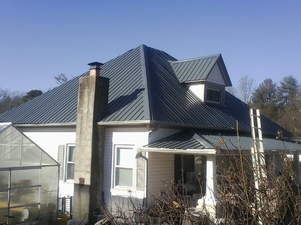 Dark blue standing seam metal roof on a white farmhouse with dormer — Slate & Tile Roof Repair by Roofing Brothers in Yarmouth