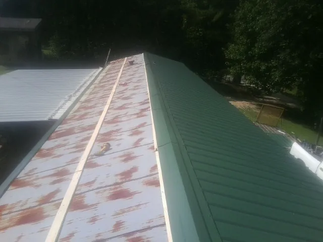 Old rusted panels beside newly installed green metal roofing — Wind Damage Roof Repair by Roofing Brothers in Yarmouth