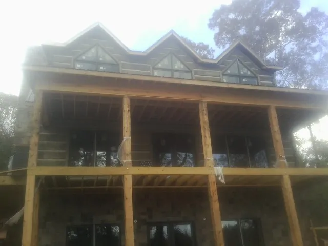 Dormers and porch framing on a large log home under construction — Roof Coating work by our crew in Yarmouth
