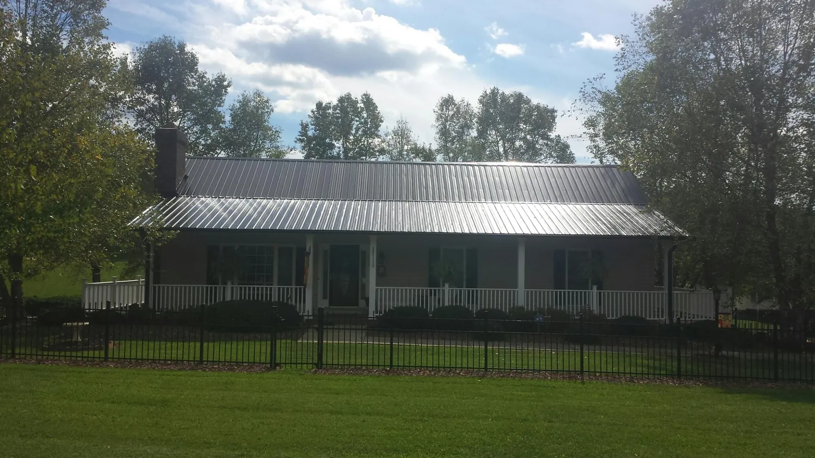Gray metal roof on a brick ranch with a full width front porch — Gutter Guard Installation work by our crew in Yarmouth