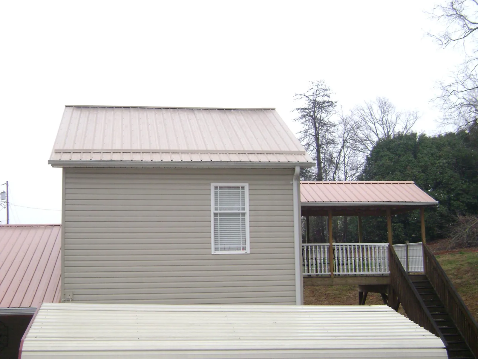 Tan metal roofs on a two story addition and attached porch, from a Roof Replacement job in Yarmouth