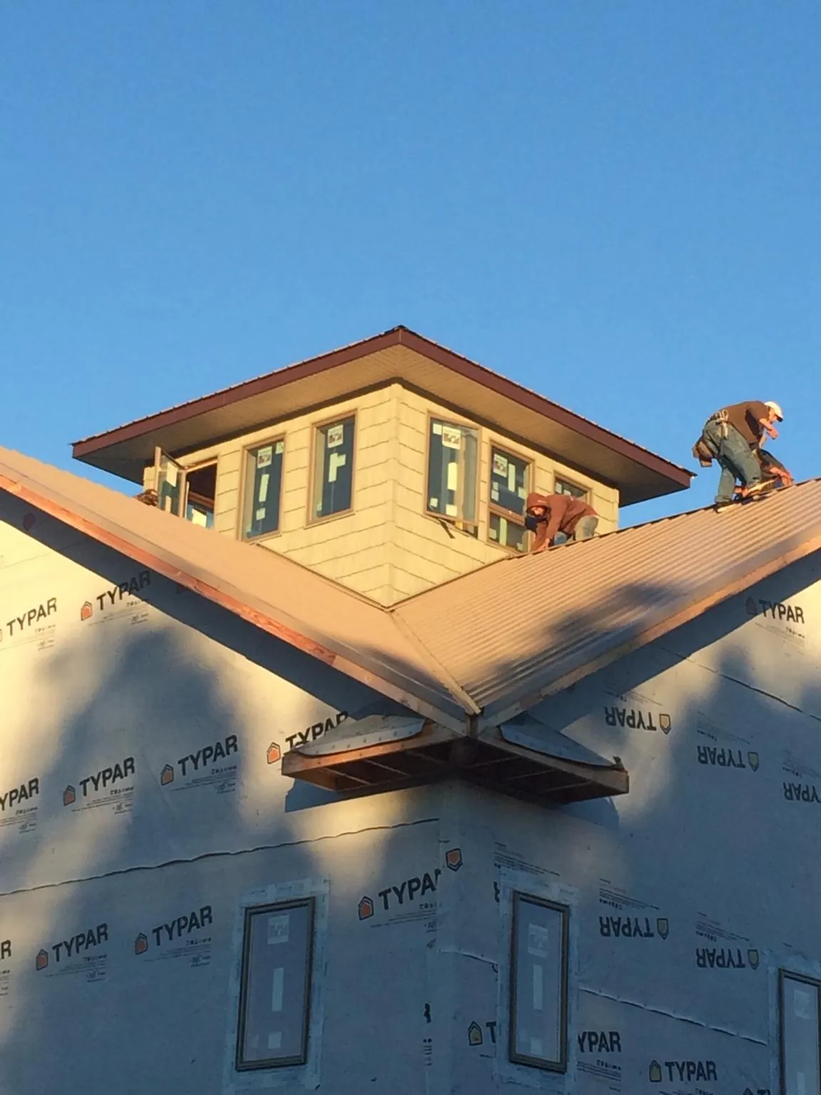 Roofers working around a rooftop cupola on a new metal roof at sunset — Roof Waterproofing in Yarmouth by Roofing Brothers